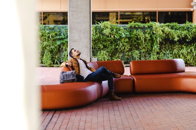 Stylish man sitting on red leather couch