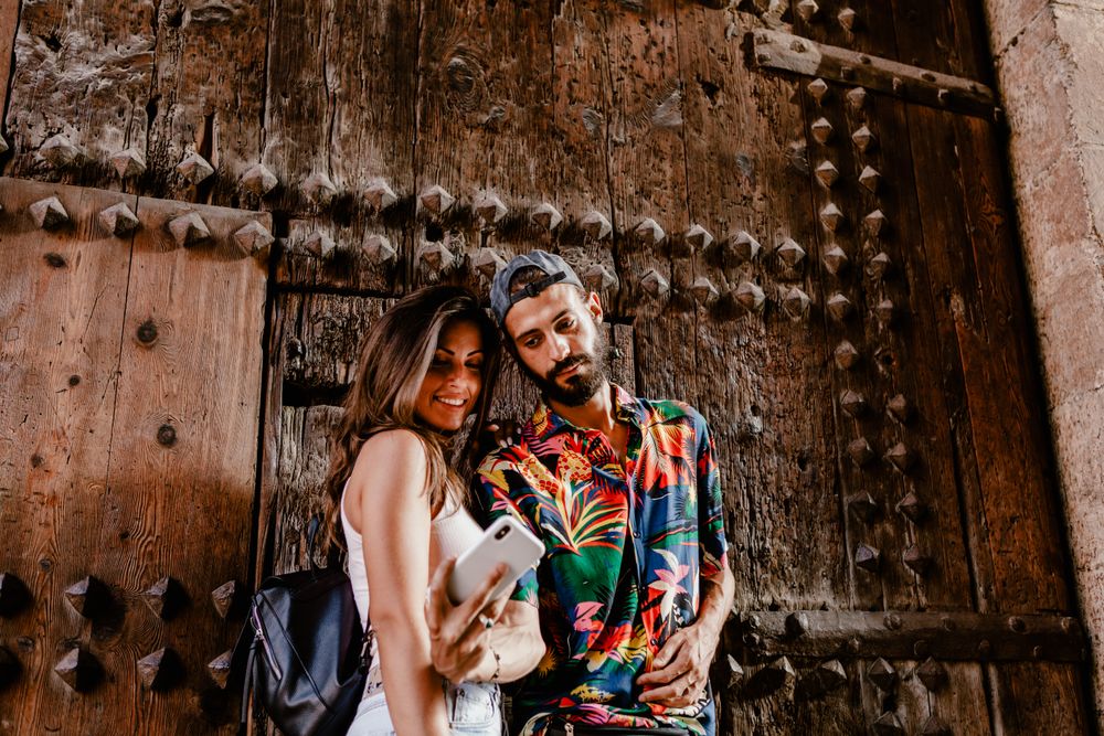 Trendy couple taking selfie on city street
