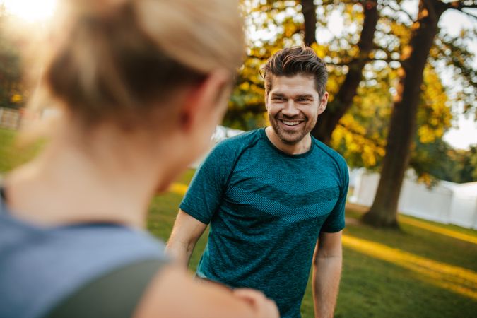Shot of handsome and fit young man smiling with woman in park