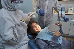 Dentist in medical uniform treating smiling boy in dental office