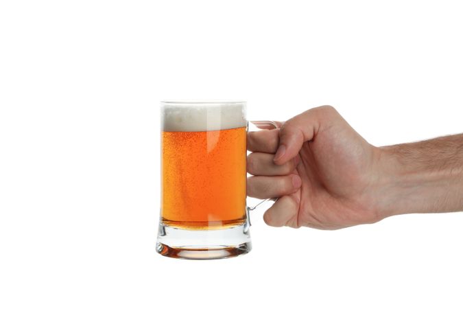 Hand holds glass of beer, isolated on light background