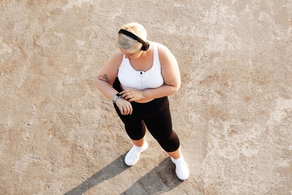 Healthy woman checking watch and wearing headphones