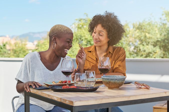 Laughing diverse women having lunch on terrace