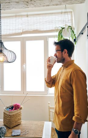 Man drinking hot tea during knitting