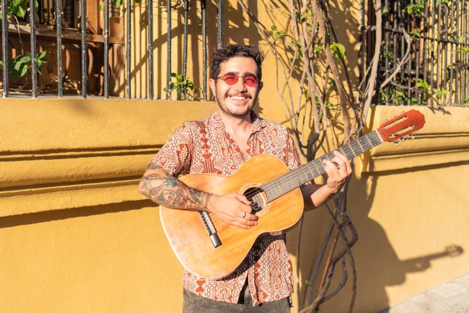 Street musician walking carrying guitar on his shoulder.