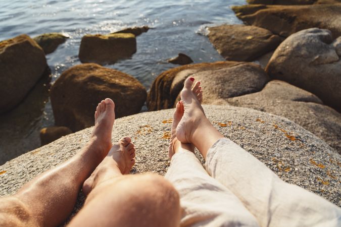 Couple chilling on stone at coast
