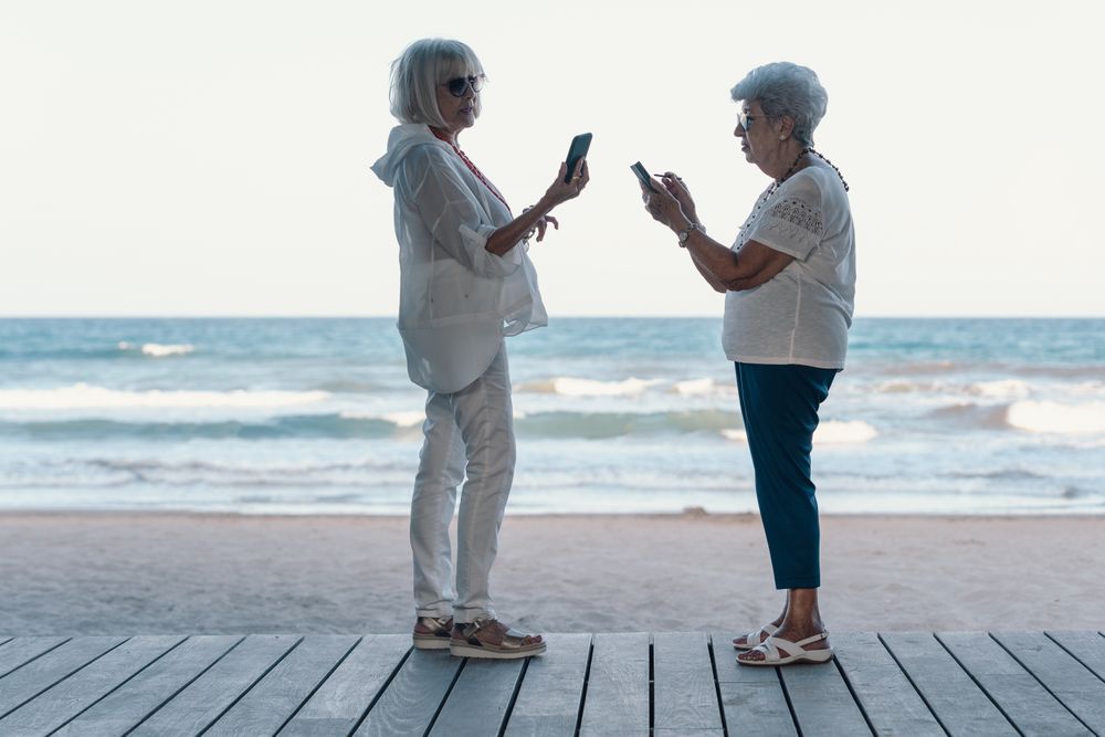 older females using phones on beach