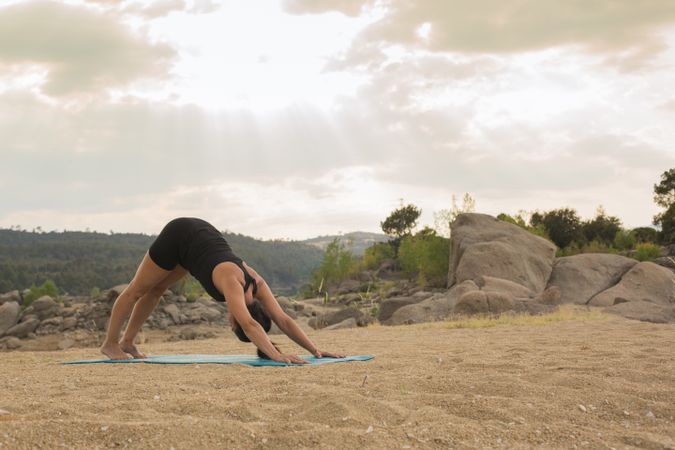Woman practicing yoga outdoors near water
