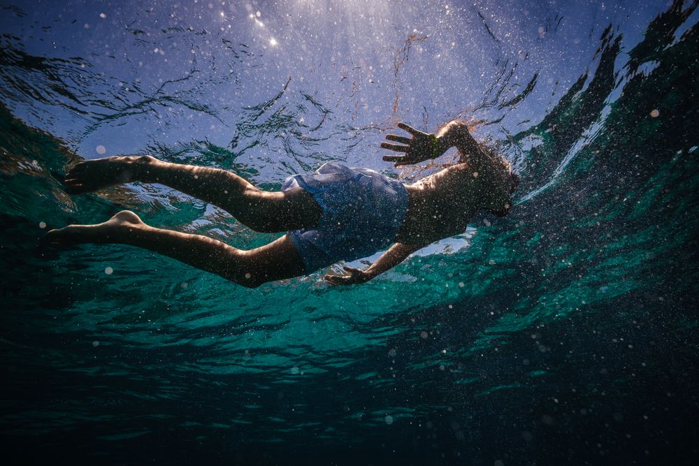 Preteen kid in diving mask snorkeling in seawater