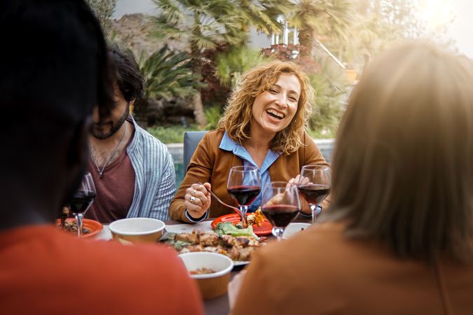 Positive woman smiles, eats, drinks and talks with friends eating at the bbq