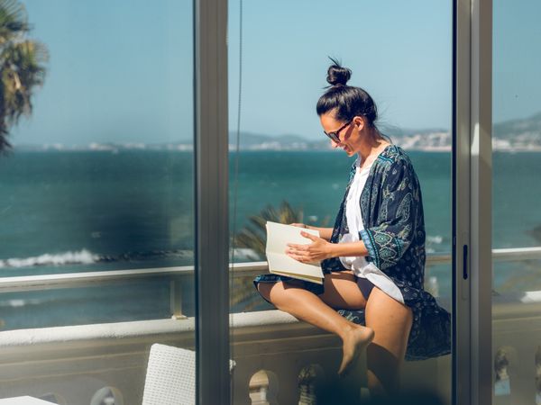 Smiling woman with notebook on balcony in hotel