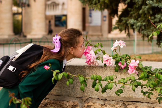 Girl in school uniform smelling pink flowers