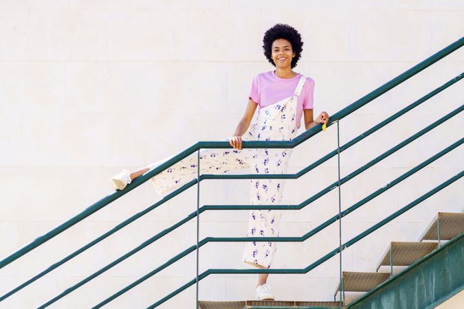 Happy woman on stairs with leg up on green handrail
