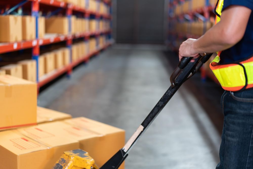 Man with trolley with boxes with high shelves in the background