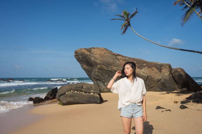 Woman in beachwear walking on sand barefoot