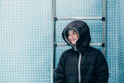 Boy in warm clothes standing in empty pool