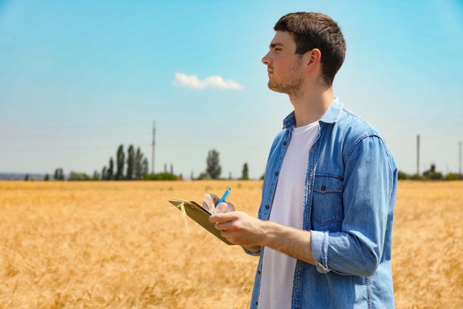 Young man with clipboard in barley field. Agriculture business. Farming