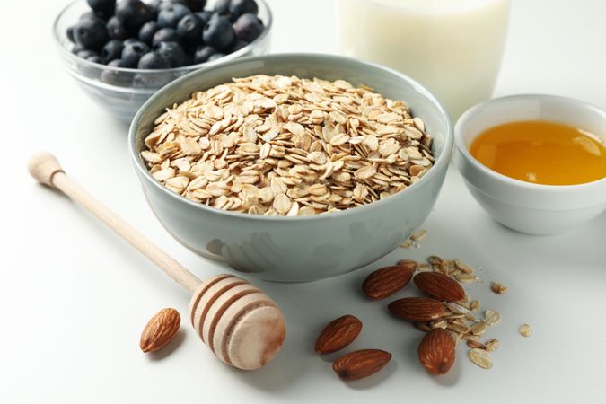 Composition with oatmeal flakes on plain background, close up. Cooking breakfast