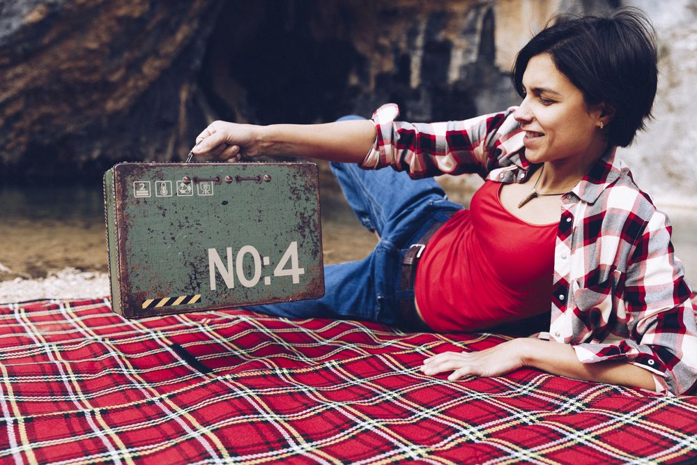Cheerful woman with old case on picnic