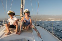 Smiling children sitting on deck of yacht in sea