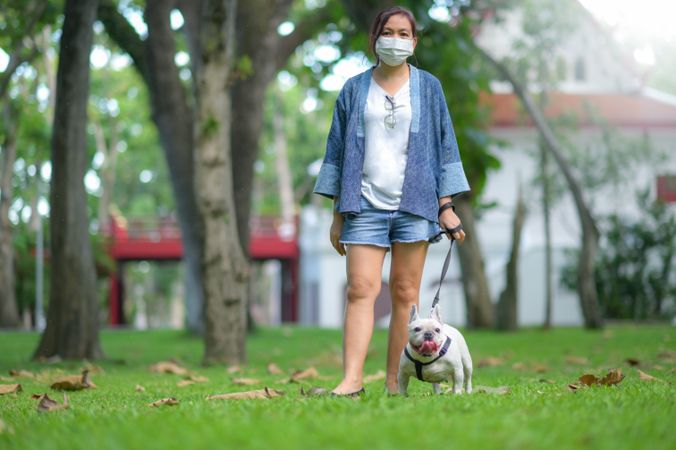 Woman with French bulldog on the lawn.