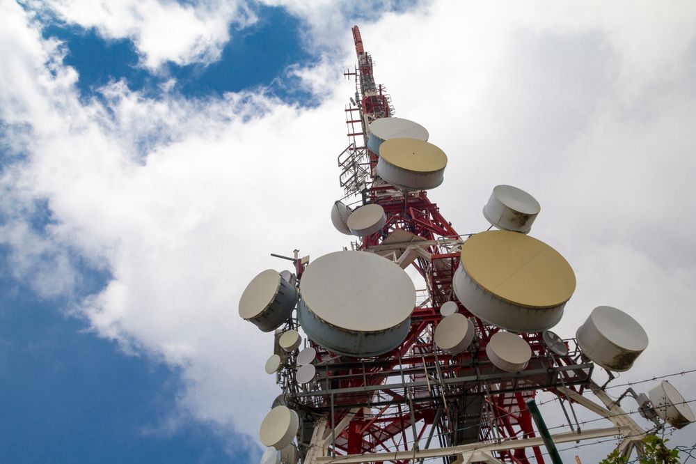 Tall Communication Tower Against a Bright Blue Sky with Clouds