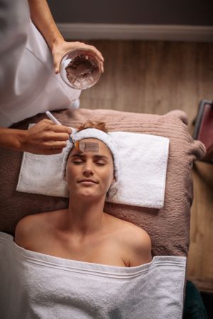 Cosmetician applying facial mask on female face