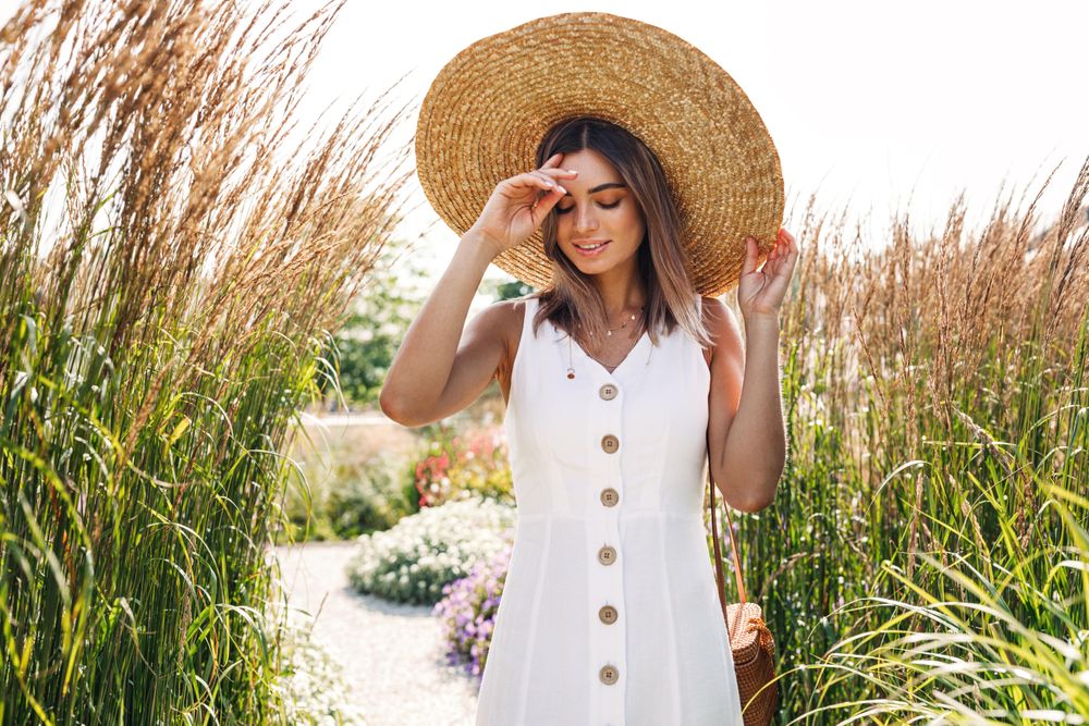 Woman walking in park in sundress and straw hat