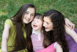 Three young women with their arms around each other sitting outside in the park
