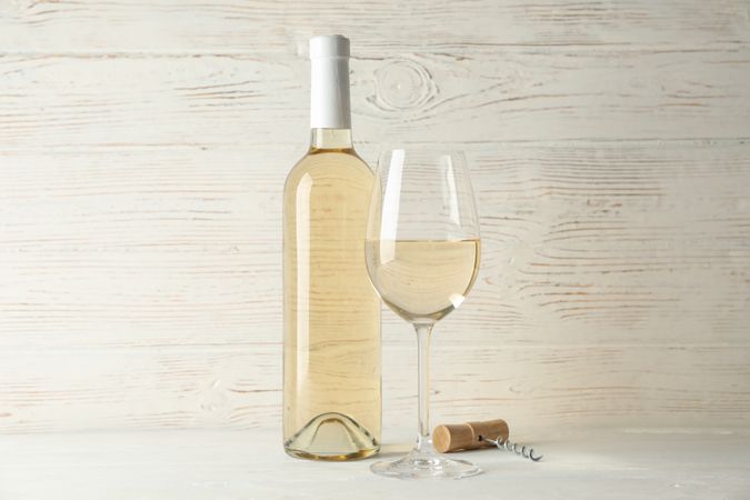 Corkscrew, bottle and glass with wine on blank wooden background, copy space
