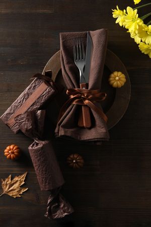 Cutlery on plate, pumpkins and flowers on wooden background, top view