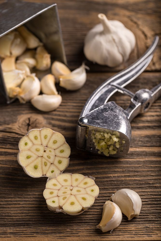 Whole halved with garlic crusher utensil