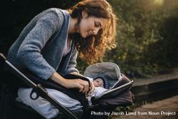 Woman fastening belt on baby in stroller 0Jnx80