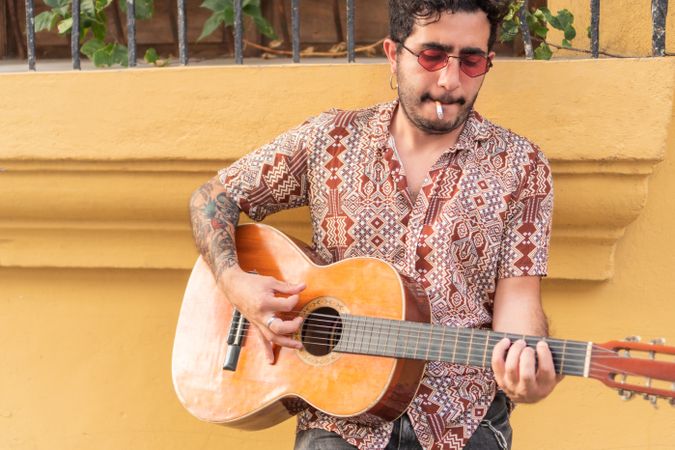 Street Musician with guitar playing guitar while smoking. Guitarist standing in the street.