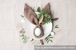 Napkin in rabbit ear shape on plate with egg in center surrounded by foliage 5kWg65
