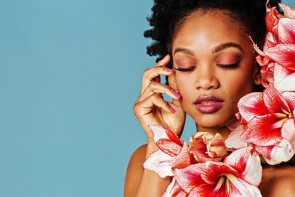 Studio shoot of Black woman surrounded by flowers with copy space