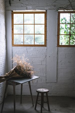 Bunch of plant in paper on table near stool in grey room