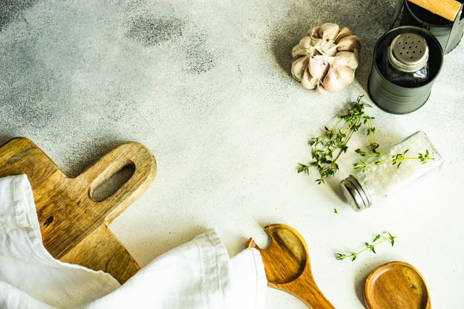 Top view of salt and pepper shakers, thyme and garlic on wooden board with copy space