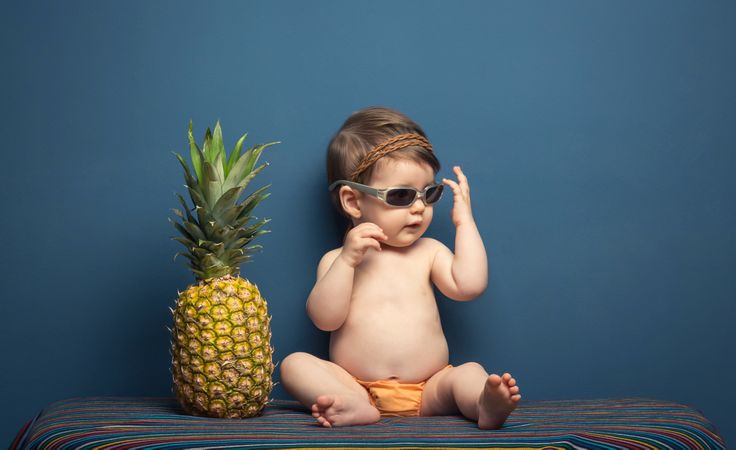 Happy baby playing with a pineapple