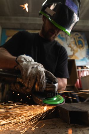 Male worker using electric grinder in workshop