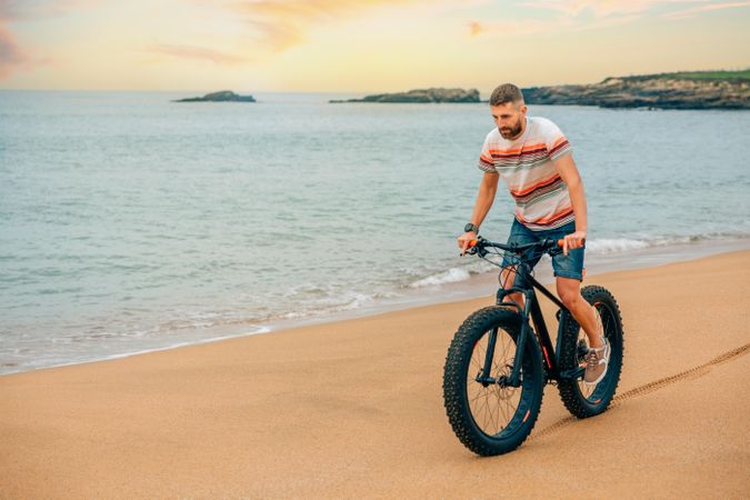 White male riding bicycle on beautiful coast