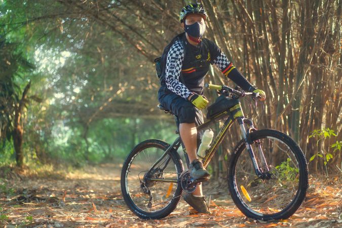Man with facemask riding a sports bicycle in the wood