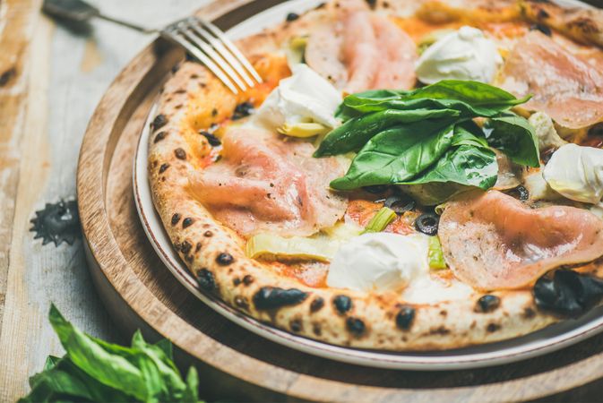 Freshly made wood fire oven pizza with spinach, ham and olives, close up, horizontal composition