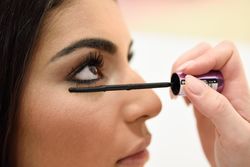 Woman applying mascara to female’s face
