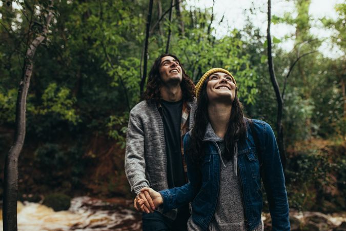 Young woman with her boyfriend in a forest, both looking up and smiling
