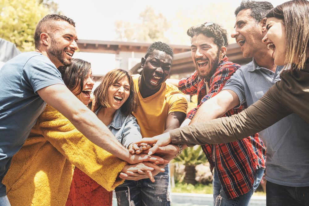 Happy multi-ethnic teamwork of people having fun joining hands together