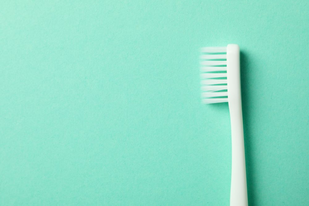 Toothbrush on mint background, space for text