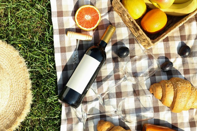 Composition with wine, croissants, fruits and towel on grass, top view