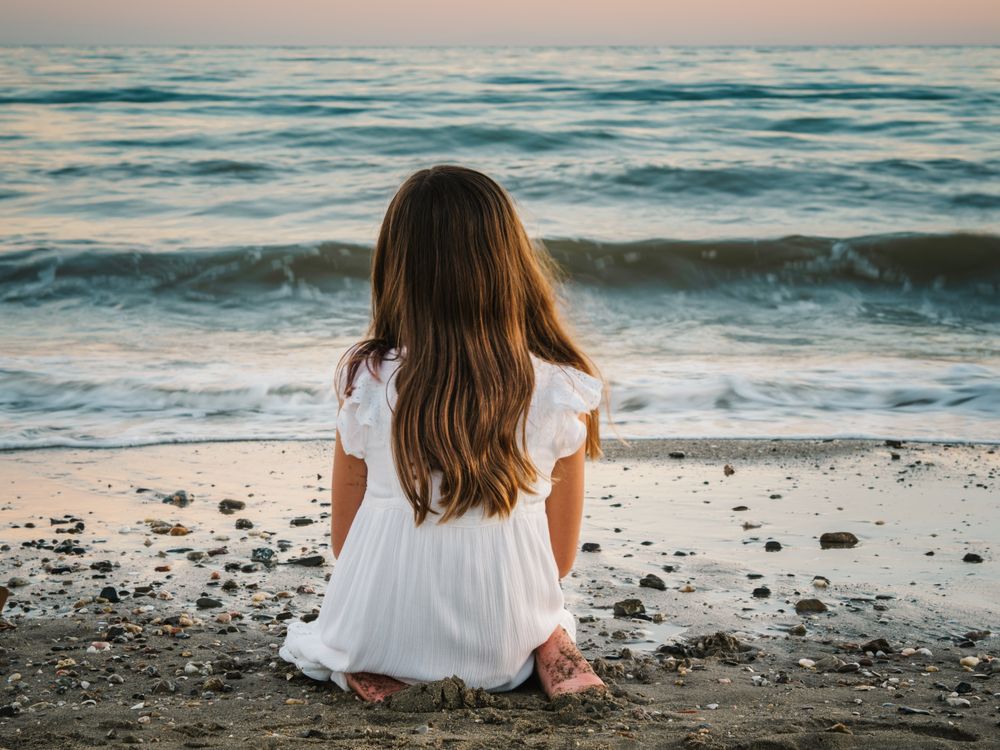 back view girl sitting on beach in daylight