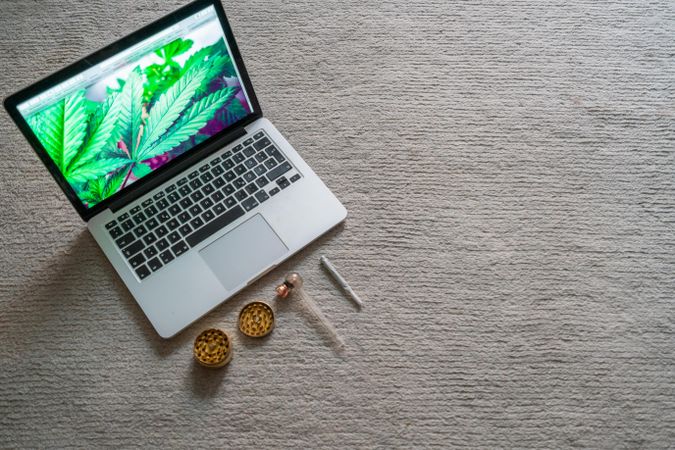 Laptop with bright marijuana photo with paraphernalia on carpet